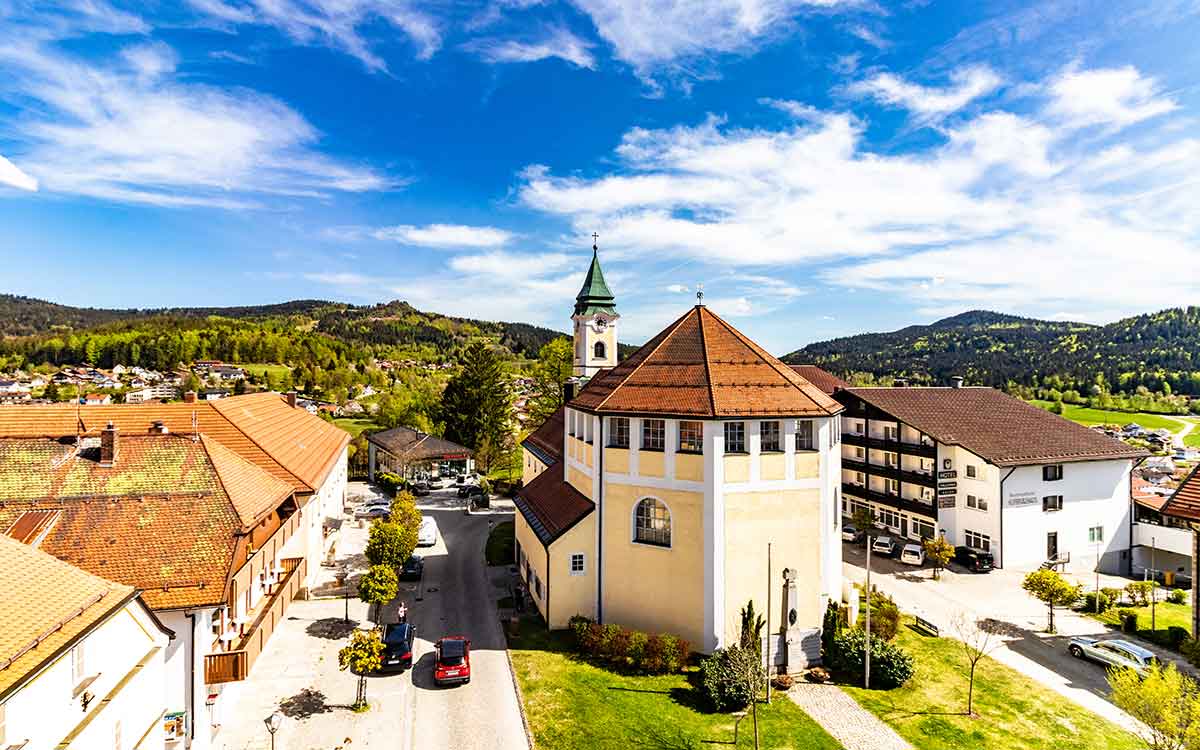 Blick auf Bodenmais im Bayerischen Wald mit der Kirche und einigen Häusern aus der Vogelperspektive, umgeben von Natur und dem Wellnesshotel Waldeck.