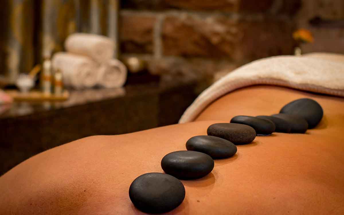 Relaxmassage im Wellnesshotel Waldeck im Bayerischen Wald mit Steinreihe auf dem Rücken.