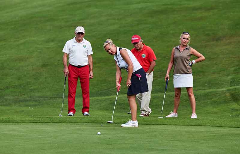 Vier Golfer im Bayerischen Wald, einer locht ein, auf dem Golfplatz Oberzwieselau in der Nähe des Wellnesshotels Waldeck.