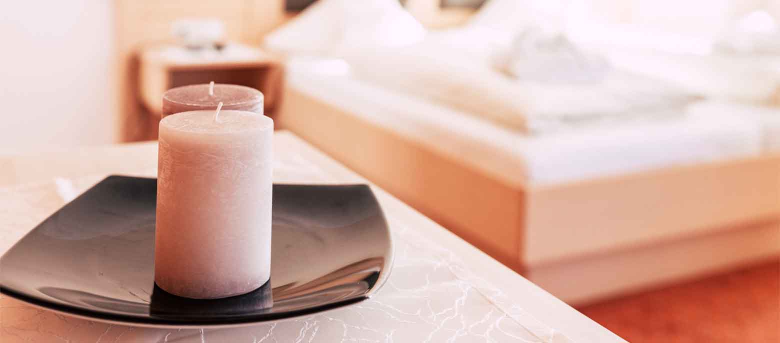 Kerze im Vordergrund, im Hintergrund das Bett eines Hotelzimmers im Wellnesshotel Waldeck Bodenmais im Bayerischen Wald.