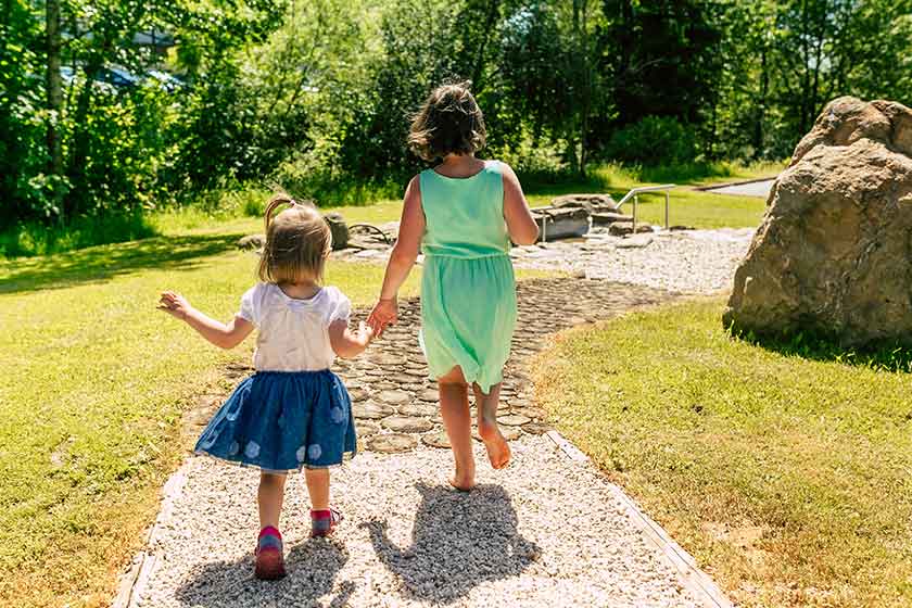 Kinder laufen auf einem schönen Weg in Richtung Pool im Wellnesshotel Waldeck im Bayerischen Wald.