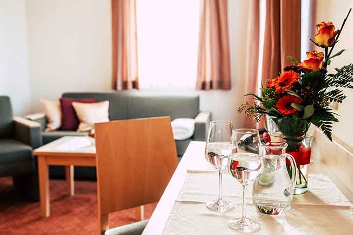 Detailansicht der Suite Mühlriegel im Wellnesshotel Waldeck, Tisch mit Gläsern und Blumen.