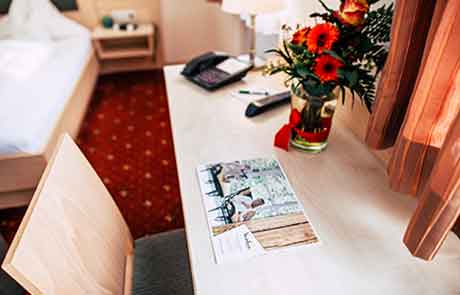 Detailansicht des Schreibtisches im Wellnesshotel Waldeck mit Vase und frischen Blumen.
