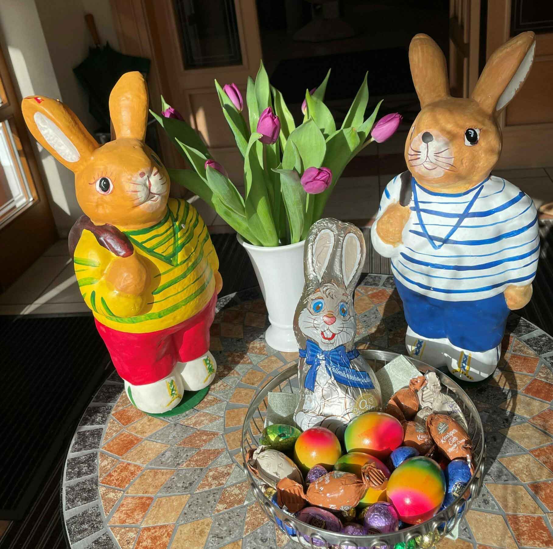 Osterhasennest umrandet von zwei Hasenfiguren, festlich dekoriert für Ostern.