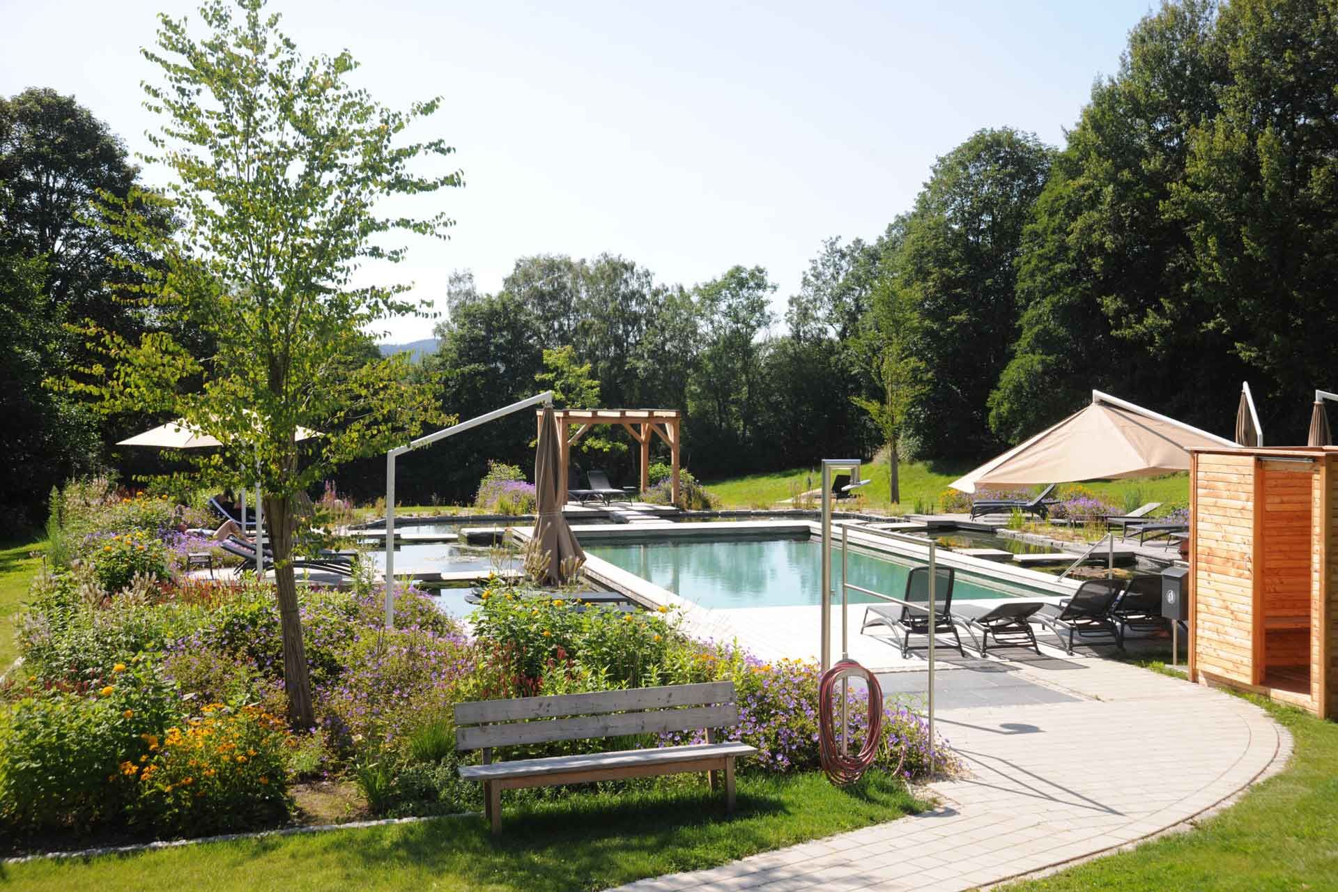 Weg zum Pool mit Außendusche und Liegen im Wellnesshotel Waldeck Bodenmais im Bayerischen Wald.